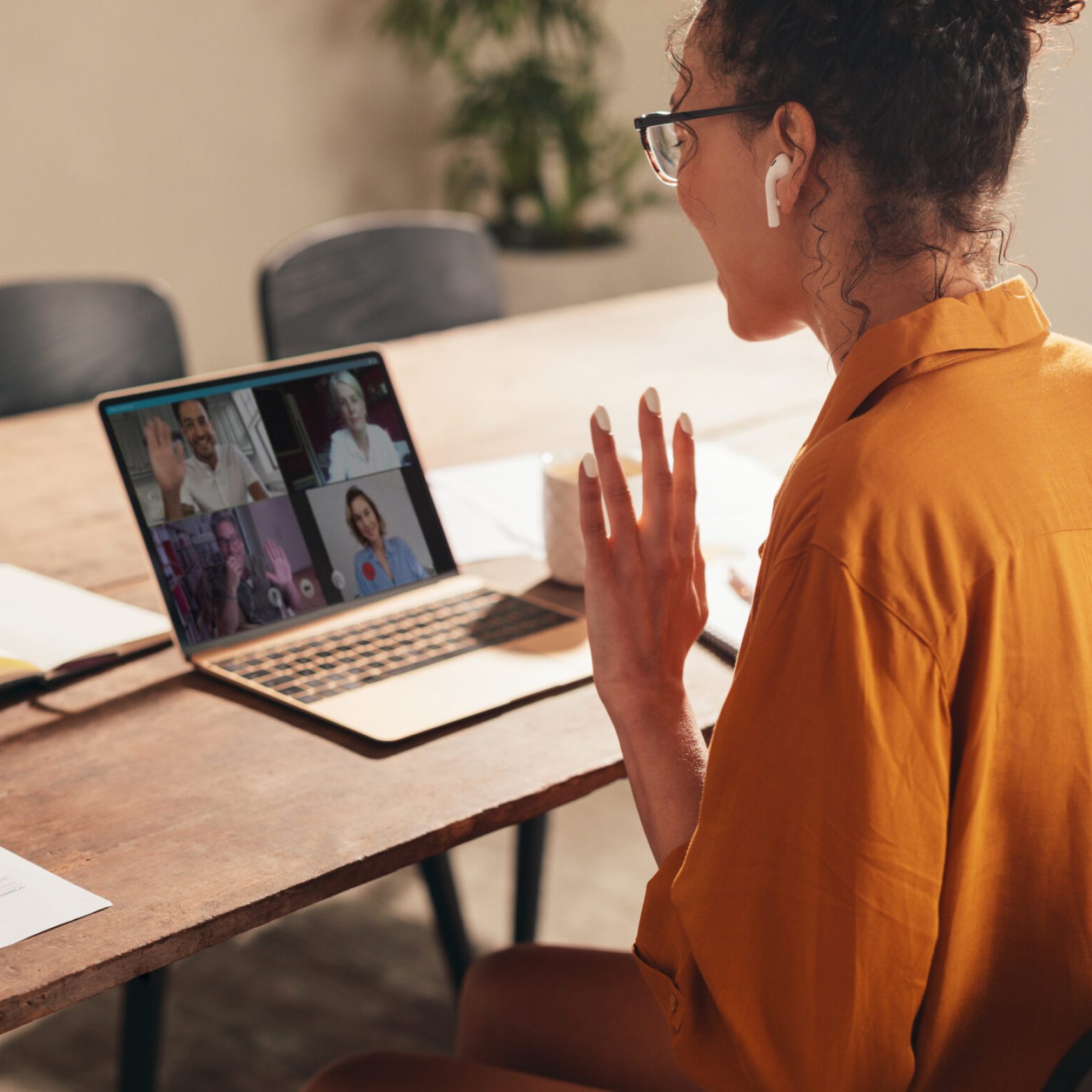 Businesswoman at home having a video conference call with colleagues. Woman greeting coworker during a web conference.